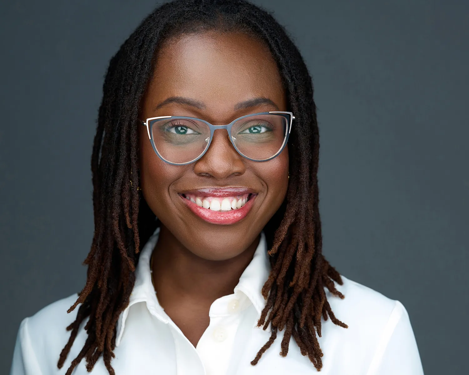 Business headshot of a smiling woman wearing glasses and a white blouse in Fort Lauderdale.