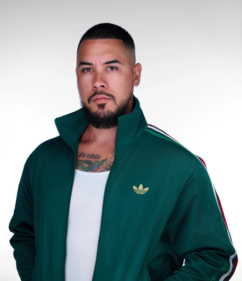 Commercial actor portrait of a bearded man in a green track jacket against a white background.