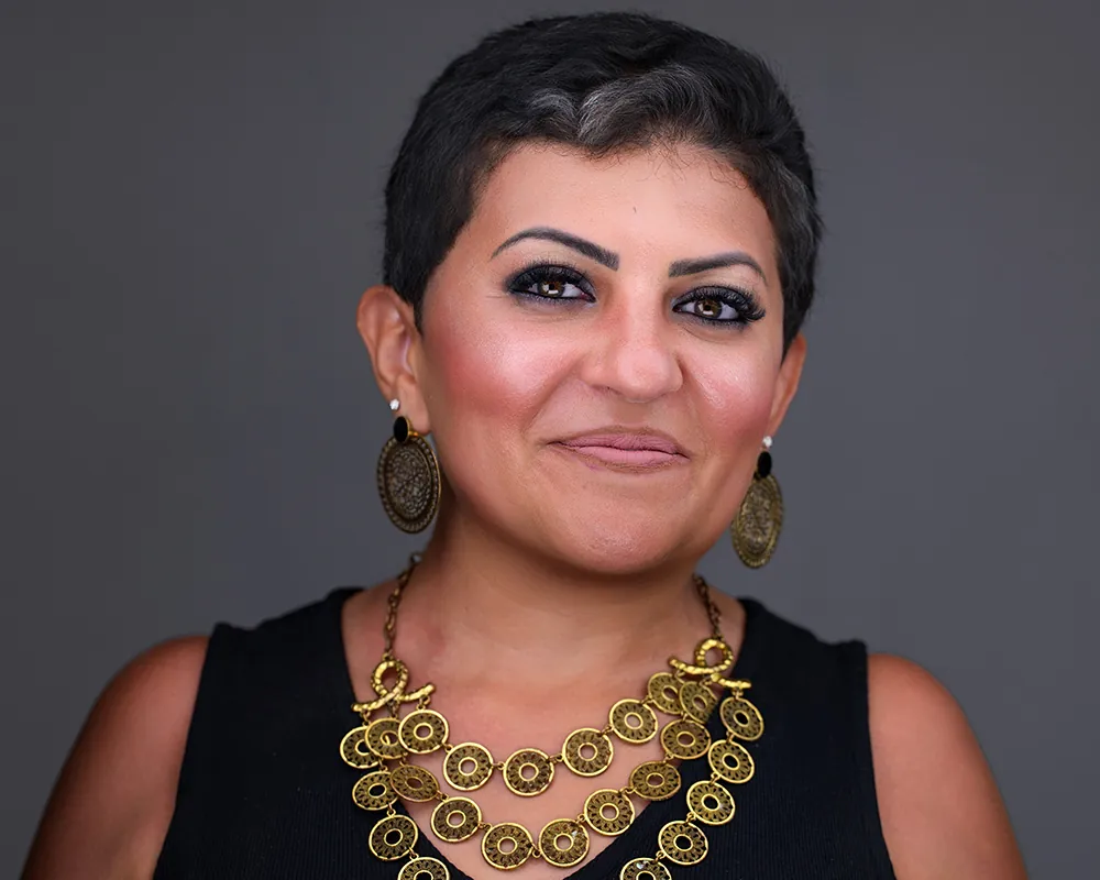 Professional convention headshot of a Miami attendee wearing a statement necklace.