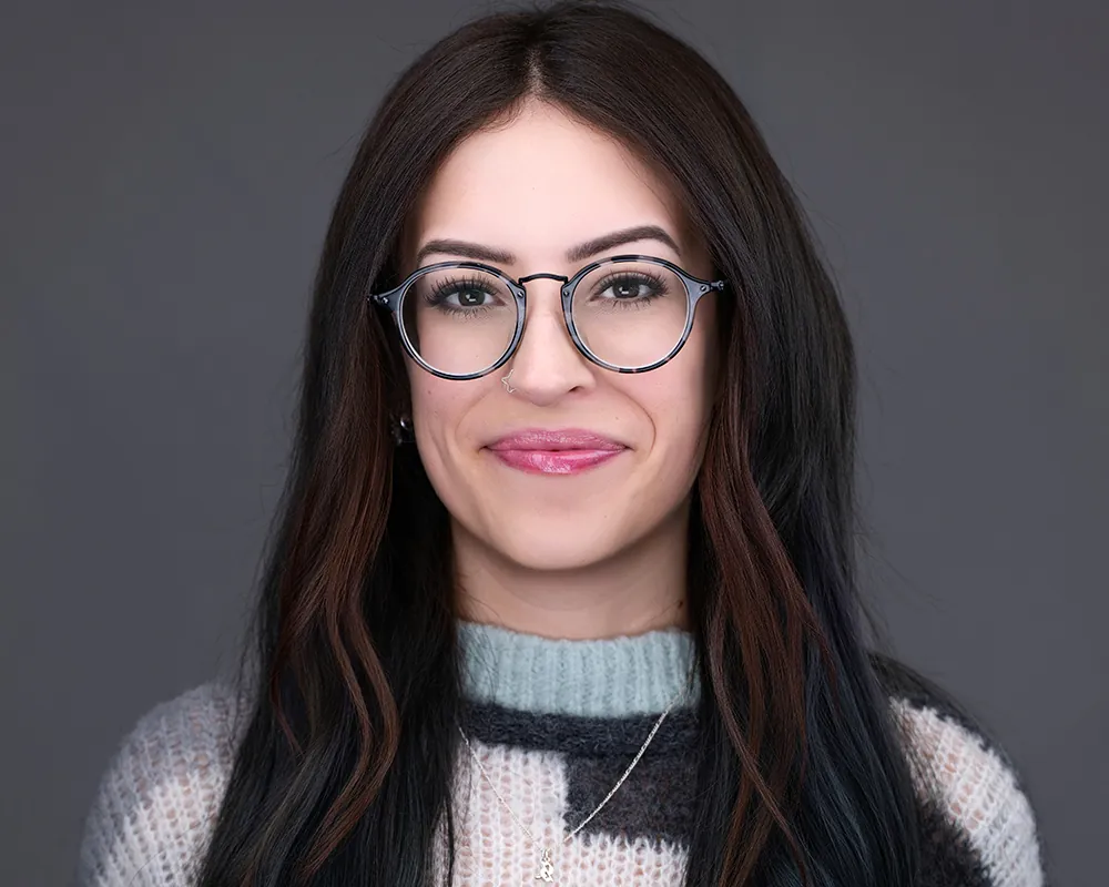 Professional headshot of a convention attendee wearing glasses against a gray background.