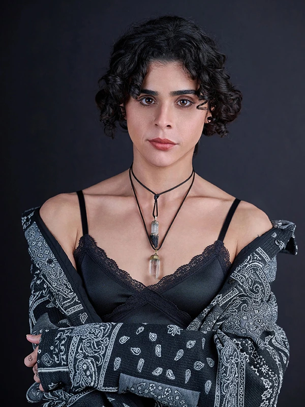 Dramatic actor headshot of a woman in black with folded arms against a dark studio background.