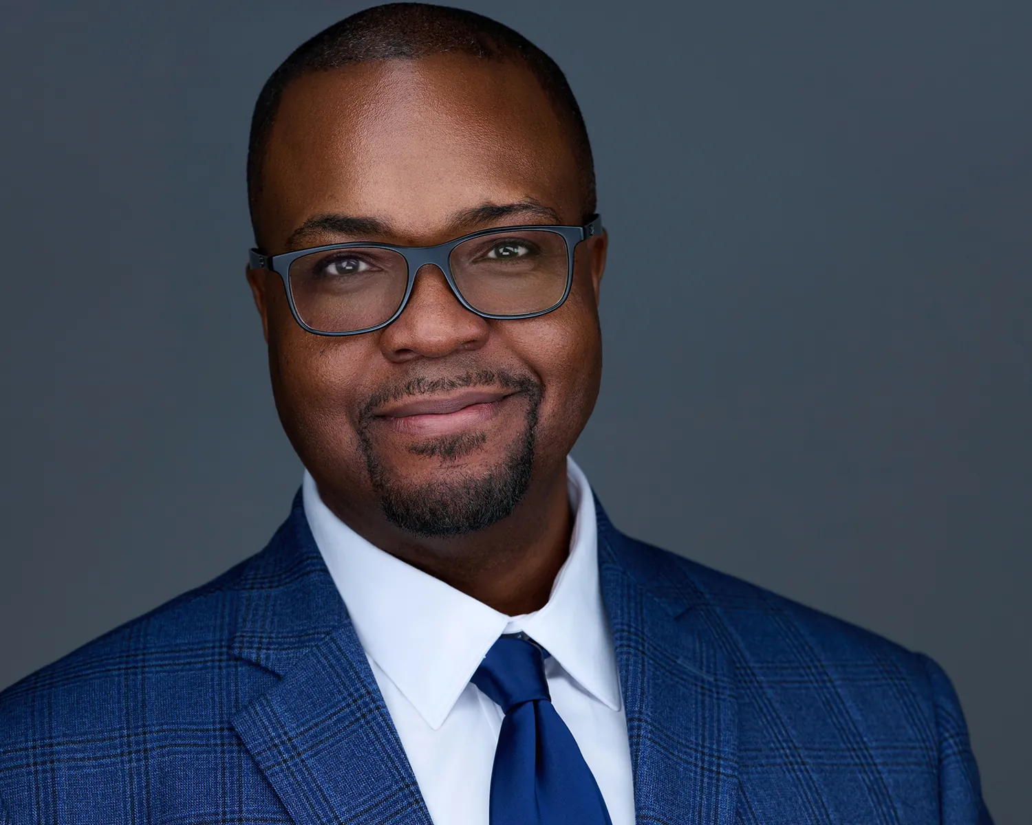 Executive headshot of a man wearing glasses and a blue suit in Fort Lauderdale.