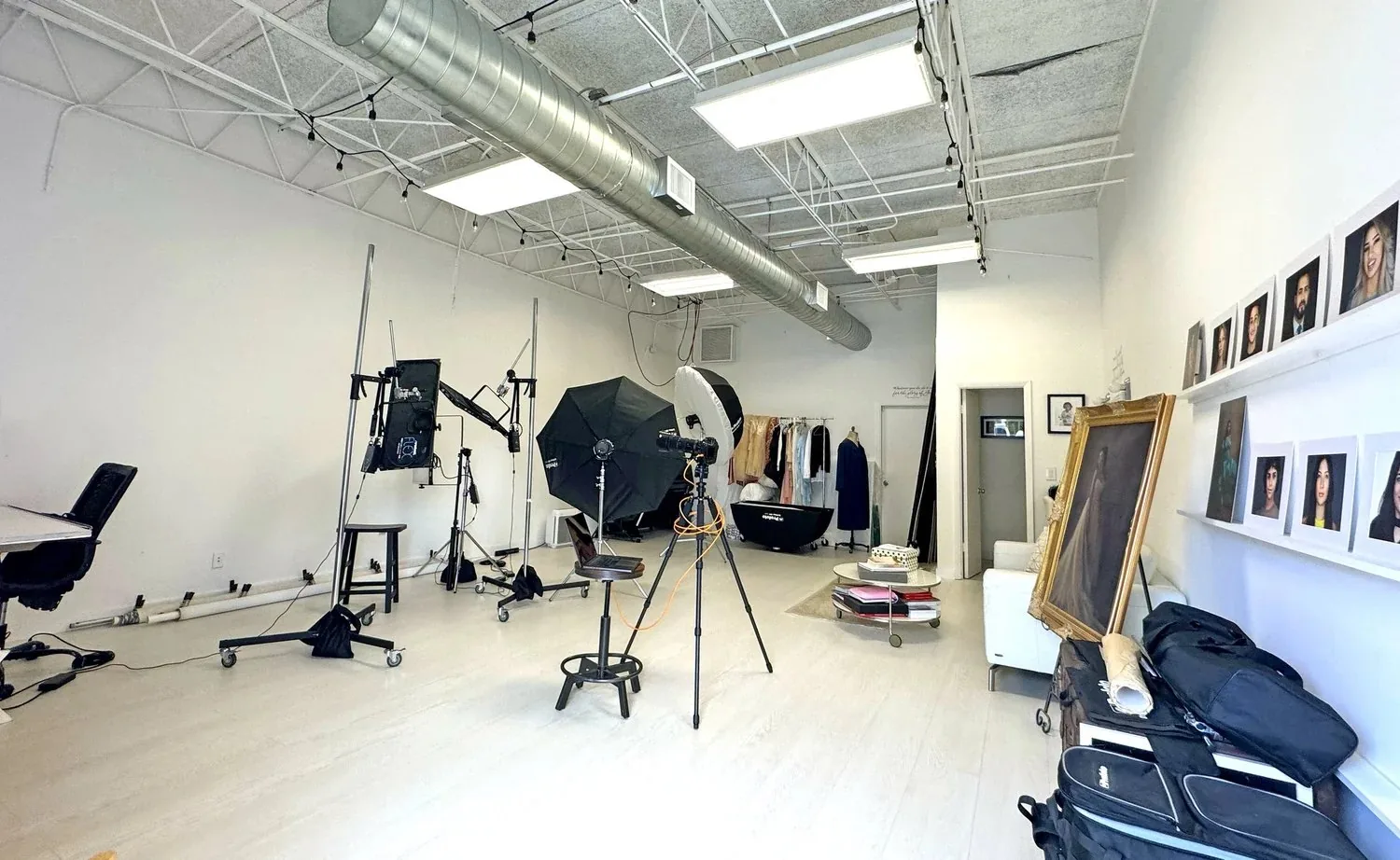 Inside the Headshots Fort Lauderdale studio in Fort Lauderdale: lighting set up, wardrobe rack, and finished portraits on the wall