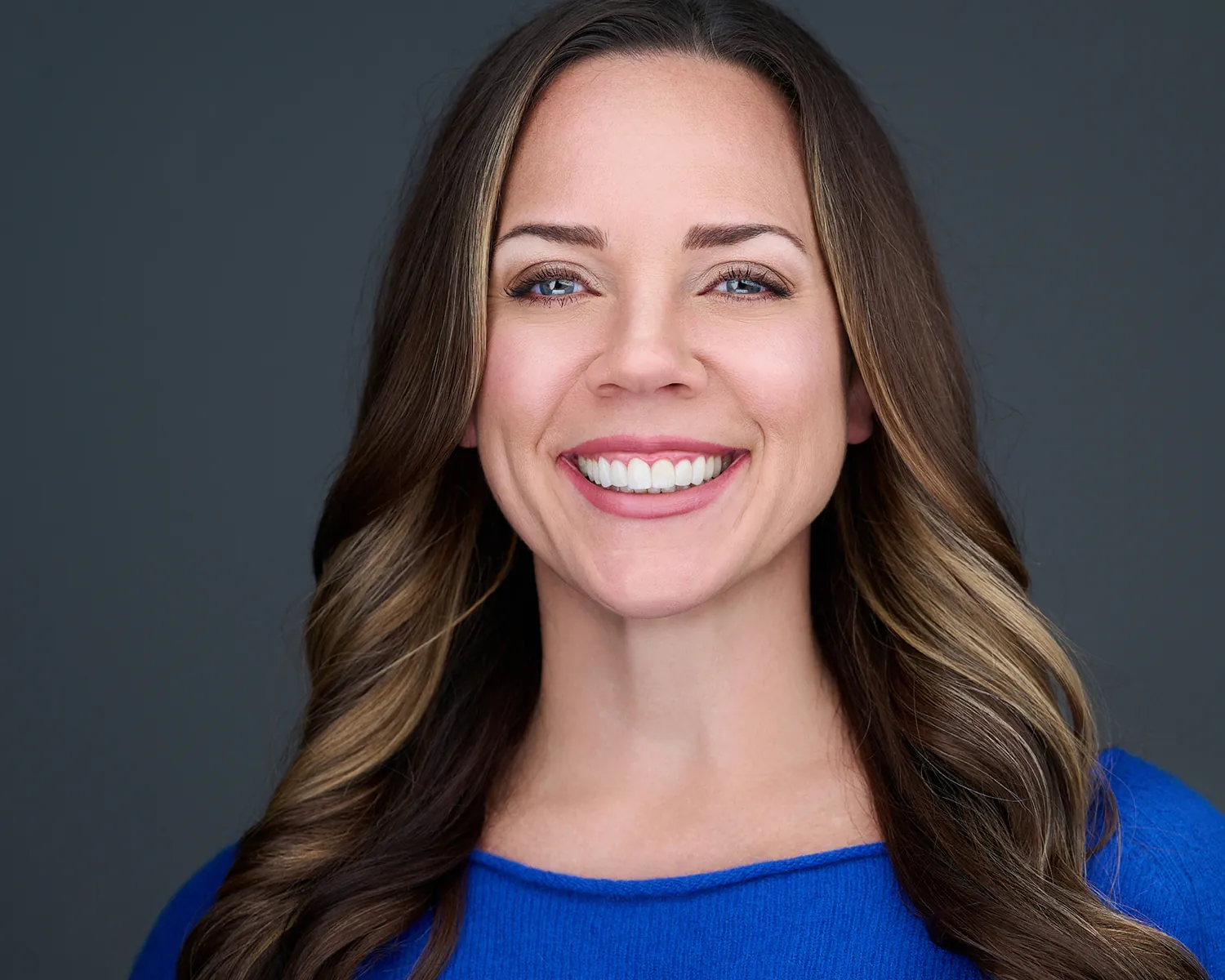 Professional headshot of a smiling woman in a blue dress photographed in Fort Lauderdale.