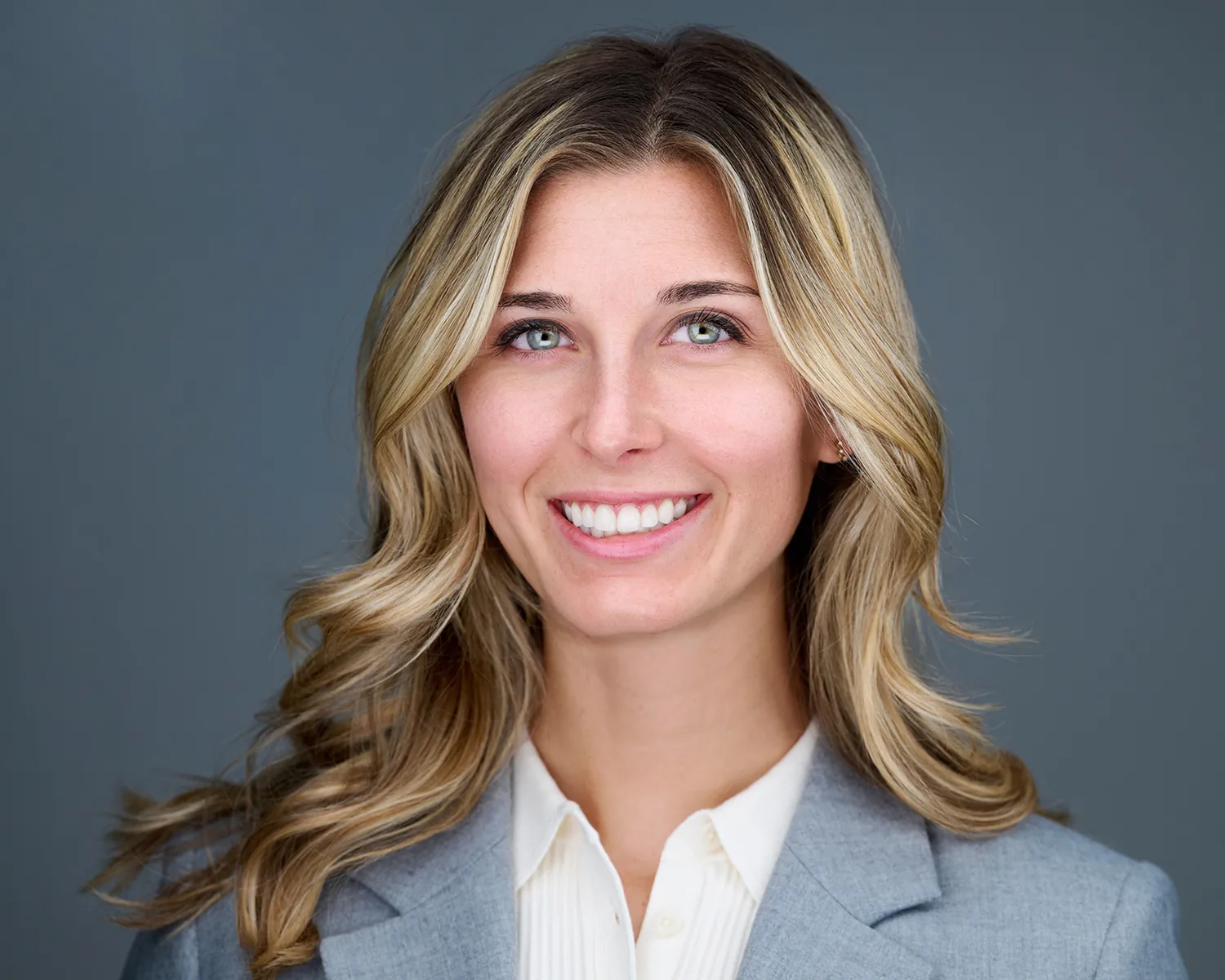Professional headshot of a smiling blonde woman in a gray blazer in Fort Lauderdale.