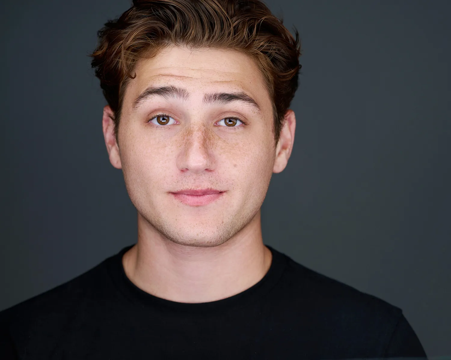 Professional headshot of a young man against a dark gray studio background in Fort Lauderdale.