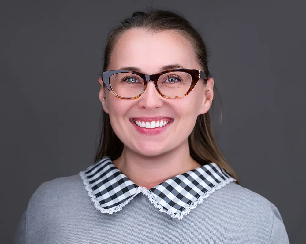 Professional team headshot of a smiling woman with glasses in Fort Lauderdale.